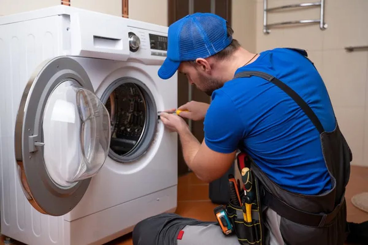 Technician working on a front-load laundry machine in a home laundry room