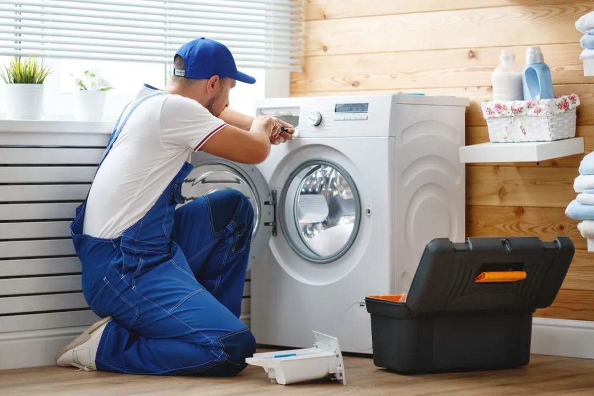 Technician servicing a front-load washing machine in a laundry room